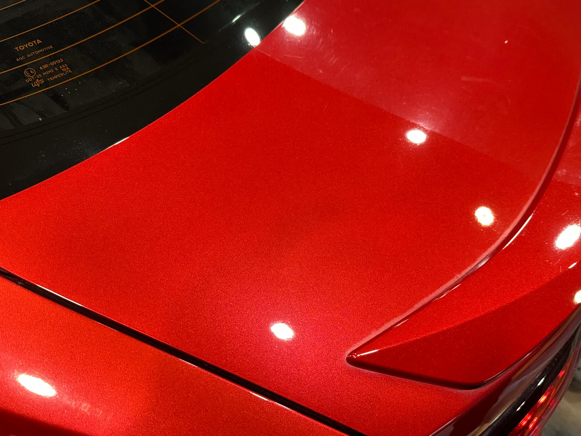 Red paint being machine polished, showing corrected paint next to swirled paint