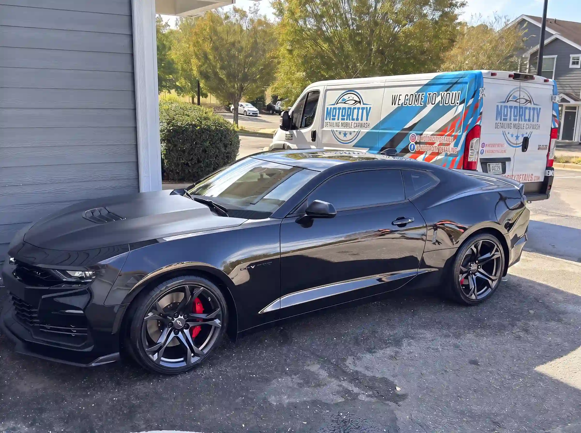 The same grey Chevrolet Camaro beside the Motorcity Detailing mobile unit after its hand wash